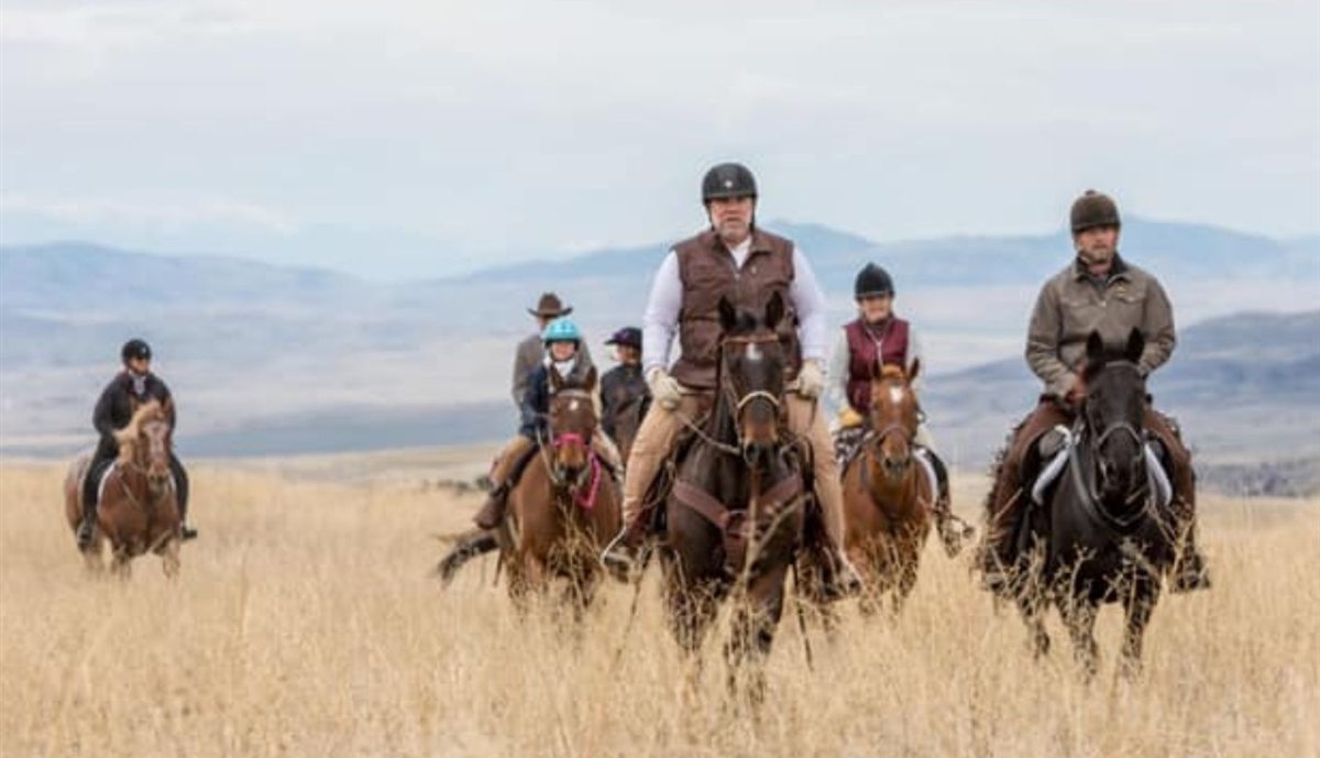 Western riders crossing open grassland